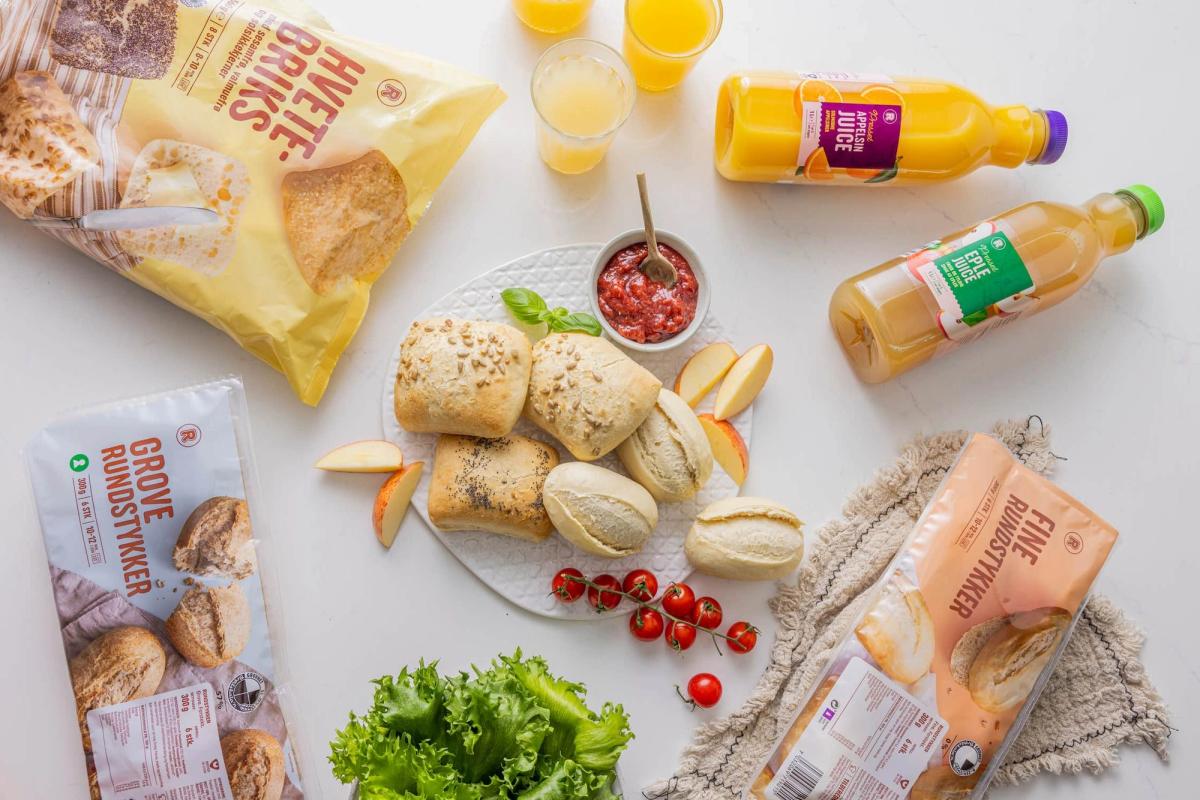 Rundstykker, knekkebrød, juice og ferskt tilbehør til frokost eller lunsj.