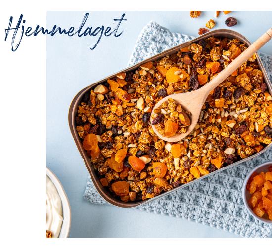 Hjemmelaget granola med tørket aprikos, rosiner og nøtter i en form, med en tresleiv oppi