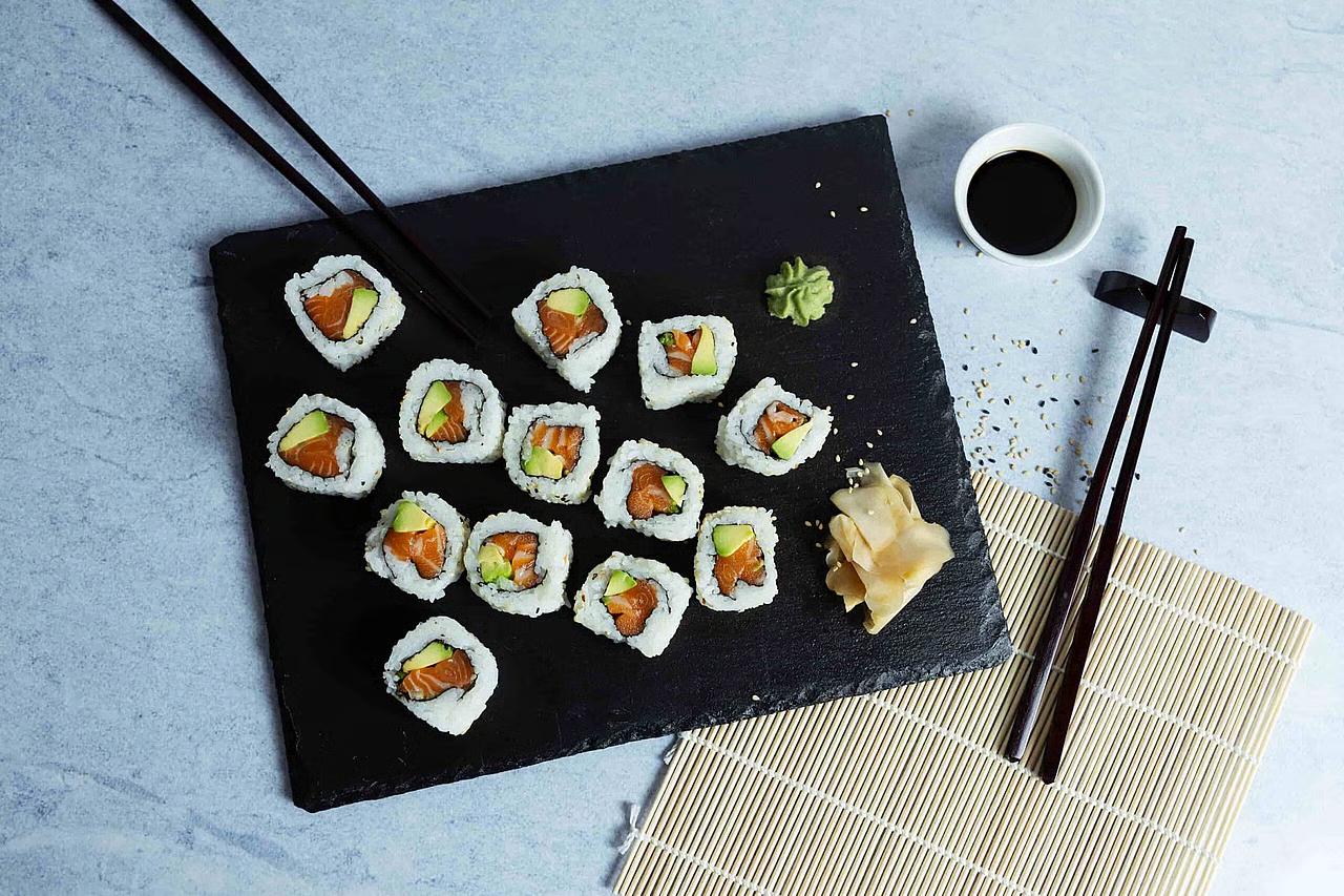 Lakse maki servert på steinfat med spisepinner og soyasaus ved siden av. 