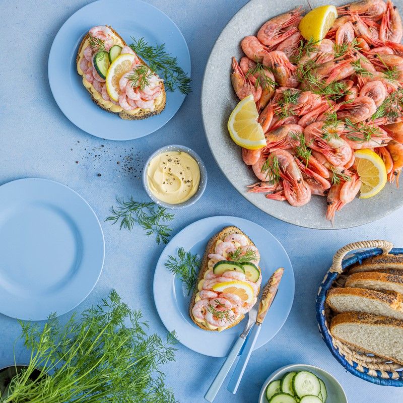 Tapasbord med spekemat, ost, reker, røkelaks, oliven, frukt, bær og brød servert på ulike fat.