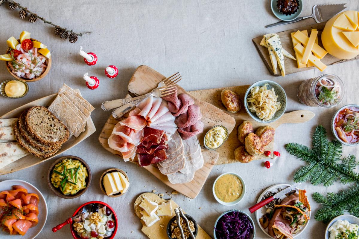Julebord med pålegg, oster, kjøttretter, brød og tradisjonelt tilbehør.
