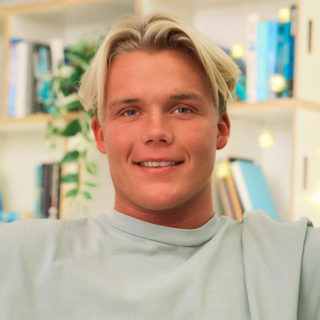 Portrett av person i lys genser foran en bokhylle.