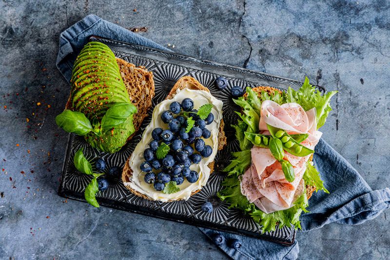 "Seafood-brett med rekebrød på blå tallerken, stor skål med reker og sitron, brød og tilbehør på blå bakgrunn"