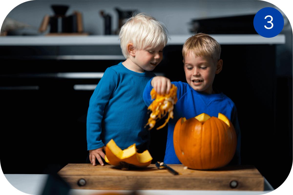 To barn tømmer et gresskar for frø og innmat før Halloween-utskjæring.